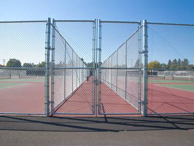 Chain link tennis court fence with round posts and middle rails.