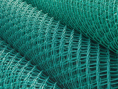Several rolls of PVC coated chain link fences are piled up.