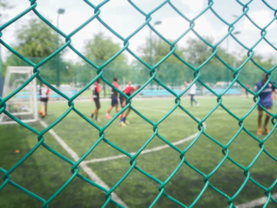 A green PVC coated football fence is installed as a security wall to keep the ball inside the court.