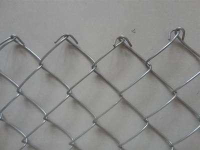 A piece of chain link mesh with knuckled edge on the ground.