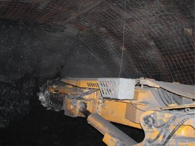 A machine is installing the welded wire mesh onto mine tunnel roof.