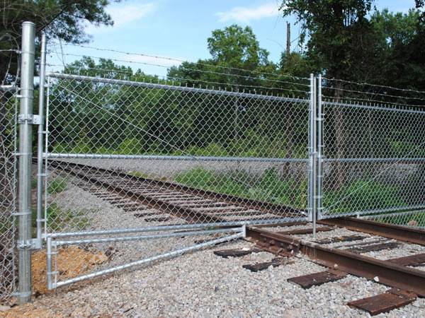 There is a galvanized chain link fabric fencing installed on a railway road.