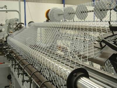 An automatic machine is producing chain link mesh.